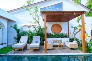 A poolside area with lounge chairs, a wooden deck, and a pergola. - Villa Moon Orchid - 3 bedroom villa (Bali)