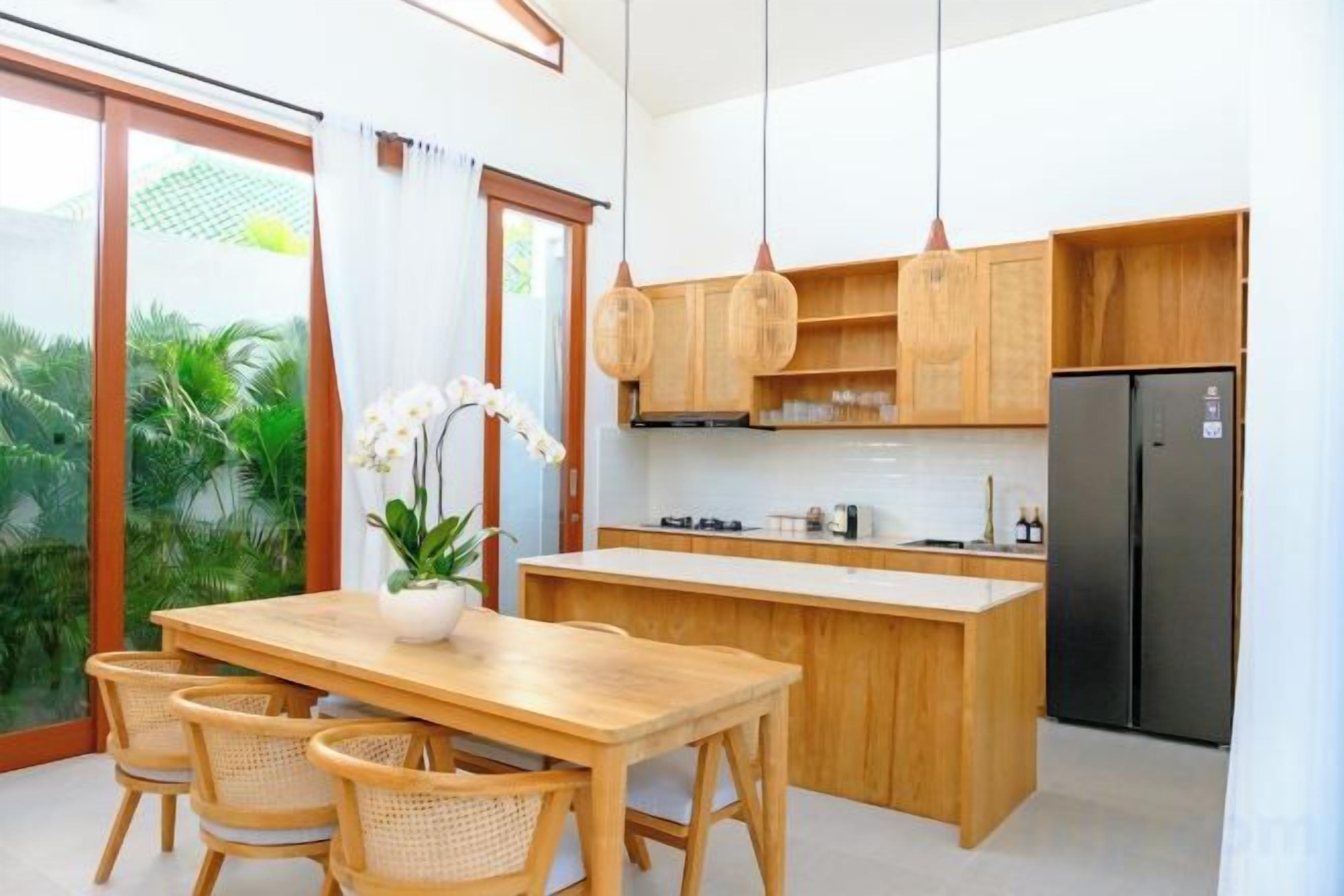 Une cuisine moderne avec des meubles en bois, un réfrigérateur noir et un coin repas comprenant une table et des chaises en bois.