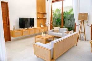 A living room with a sofa, coffee table, TV, and a plant. - Villa Moon Orchid - 3 bedroom villa (Bali)