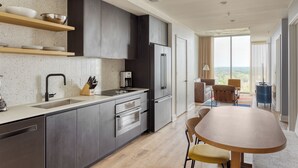 A modern kitchen with dark cabinets, stainless steel appliances, and wooden shelves. - Downtown Austin Condo | 1BR + Sleep Sofa | Natiivo (Austin)
