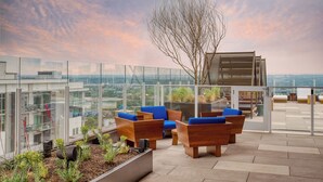 A rooftop terrace with wooden furniture and a view of the cityscape. - Downtown Austin Condo | 1BR + Sleep Sofa | Natiivo (Austin)