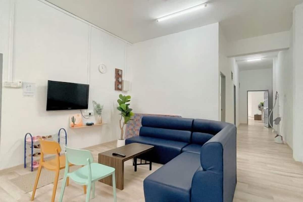 Una sala moderna con un sofá azul, televisor, mesa de centro y una planta.