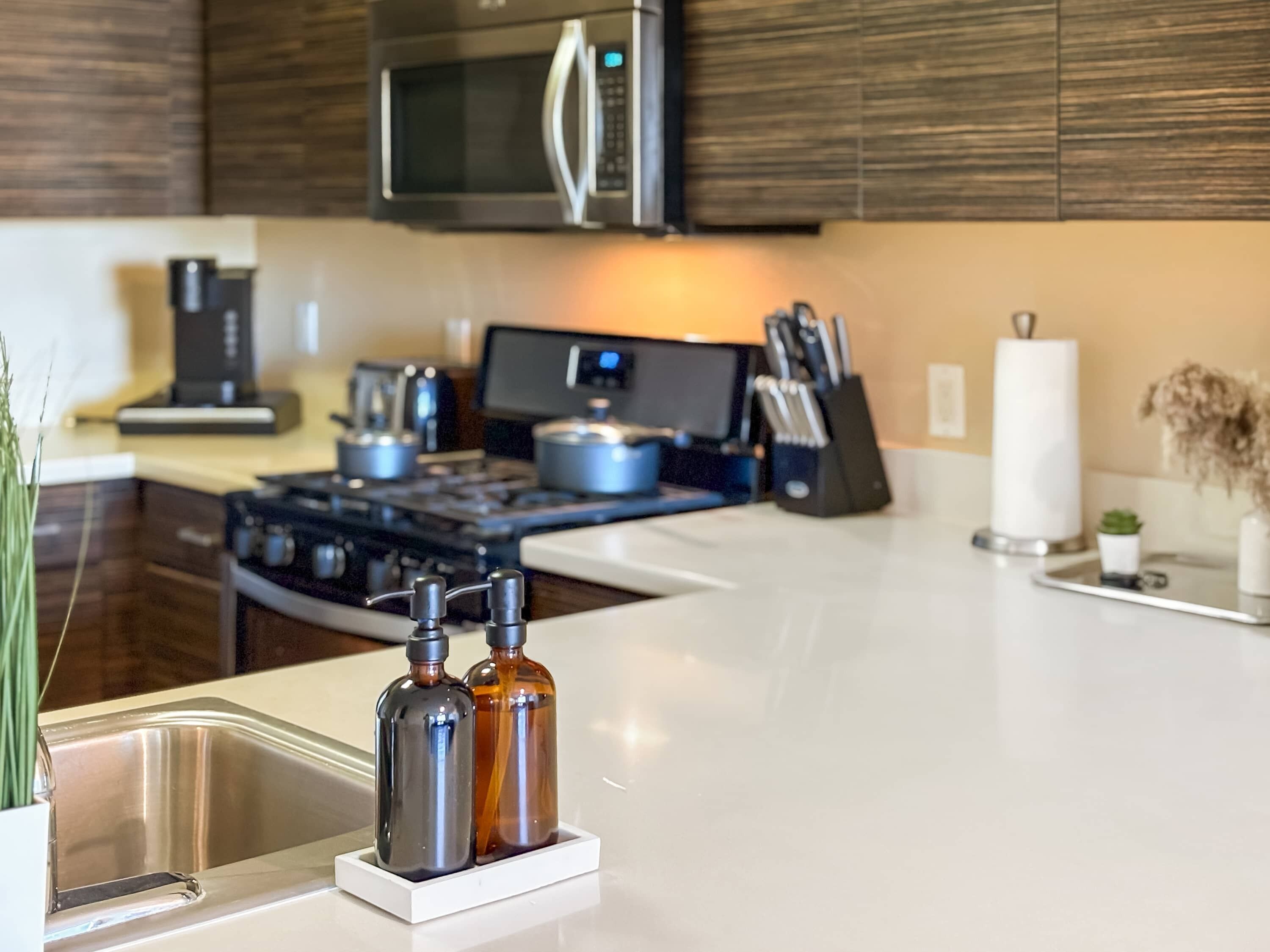 A modern kitchen with stainless steel appliances, a white countertop, and a sink.