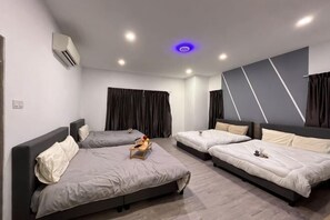 Een moderne hotelkamer met drie bedden, een flatscreen televisie en een wandairconditioner.