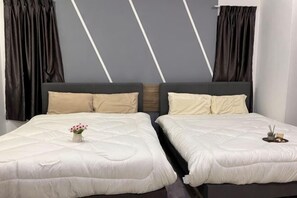 Cama doble con edredón blanco, dos almohadas, un jarrón con flores y una bandeja con velas.