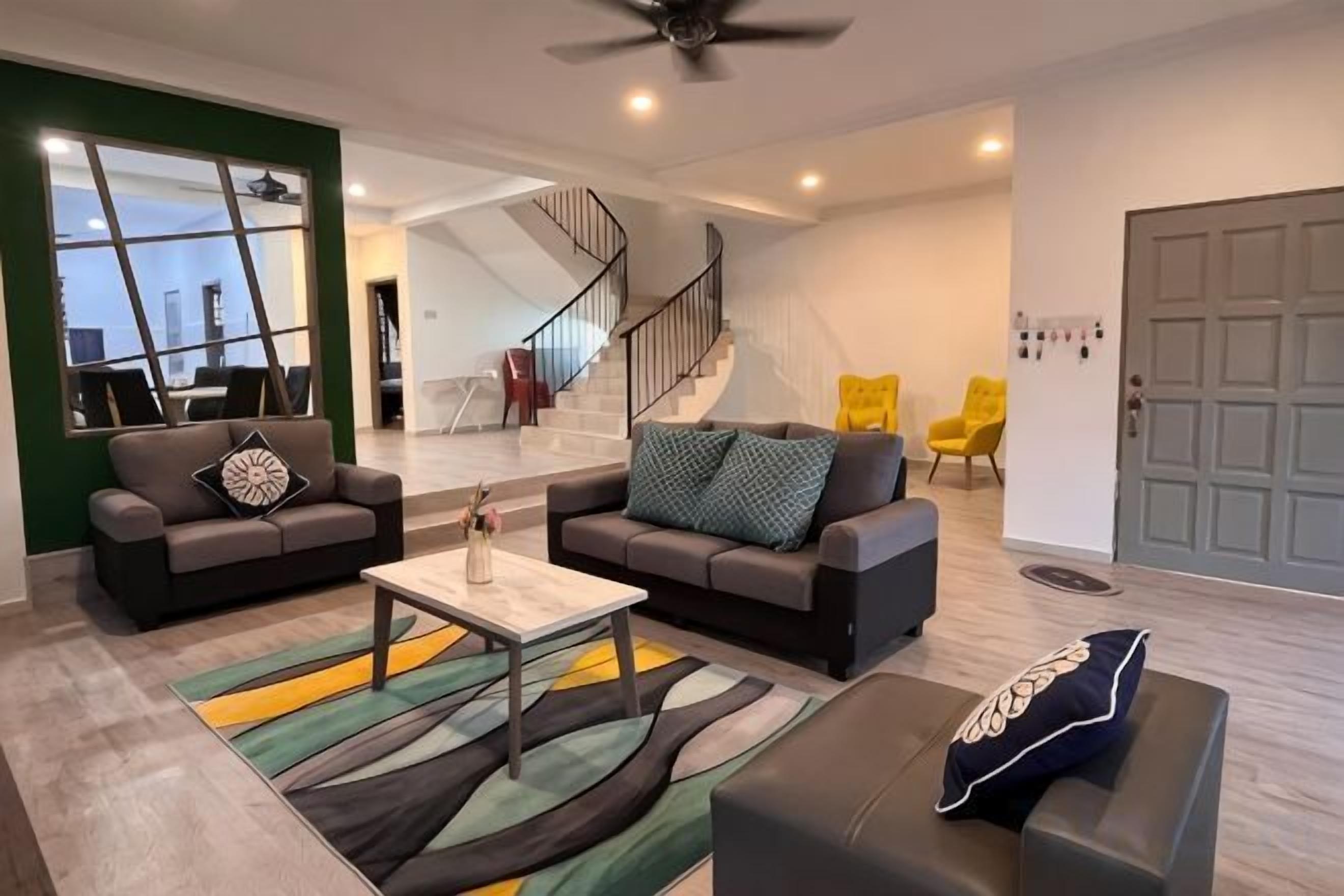 A modern living room with two sofas, a coffee table, and a staircase leading to an upper floor.