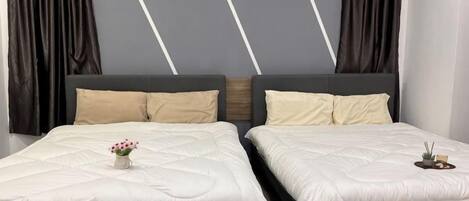 A double bed with a white duvet, two pillows, and a small vase with flowers.