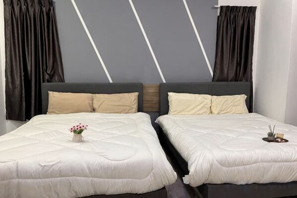 A double bed with a white duvet, two pillows, and a small vase with flowers.
