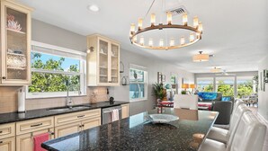 A modern kitchen with a large island, built-in cabinets, and a chandelier. - West Bay Cove 242 · Murphy Bed Office · Pool (Holmes Beach)