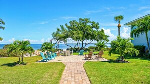 A paved pathway leading to outdoor seating with a view of the ocean. - West Bay Cove 242 · Murphy Bed Office · Pool (Holmes Beach)
