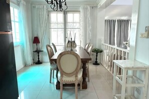 A dining area with a long table, chairs, and a chandelier. - Warisa Garden Pool Villa (Pattaya)