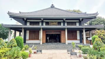 A traditional building with a tiled roof and wooden doors, surrounded by potted plants and a stone pathway.