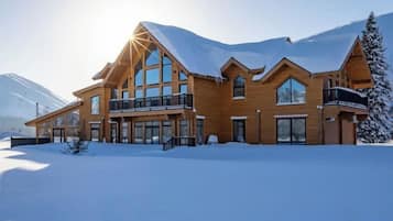 Un grand chalet en bois doté de nombreux balcons et de grandes fenêtres, entouré de neige.