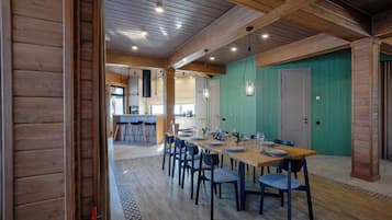 Un espace repas avec une longue table, des chaises et une cuisine en arrière-plan.