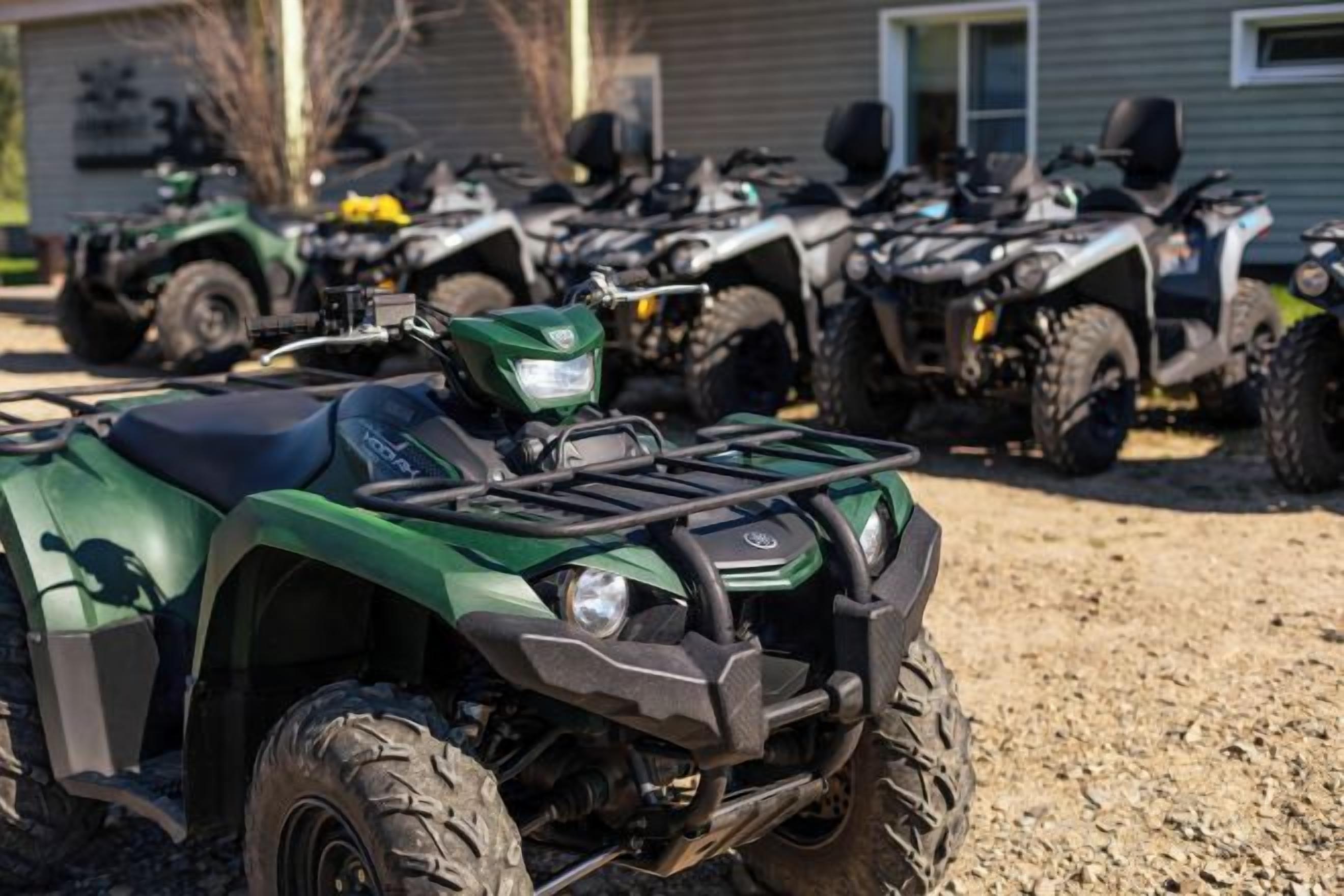 A row of ATVs parked in a gravel area.