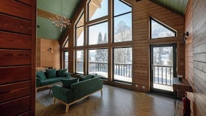 Une pièce spacieuse avec de grandes fenêtres, un plafond en bois et un canapé vert.