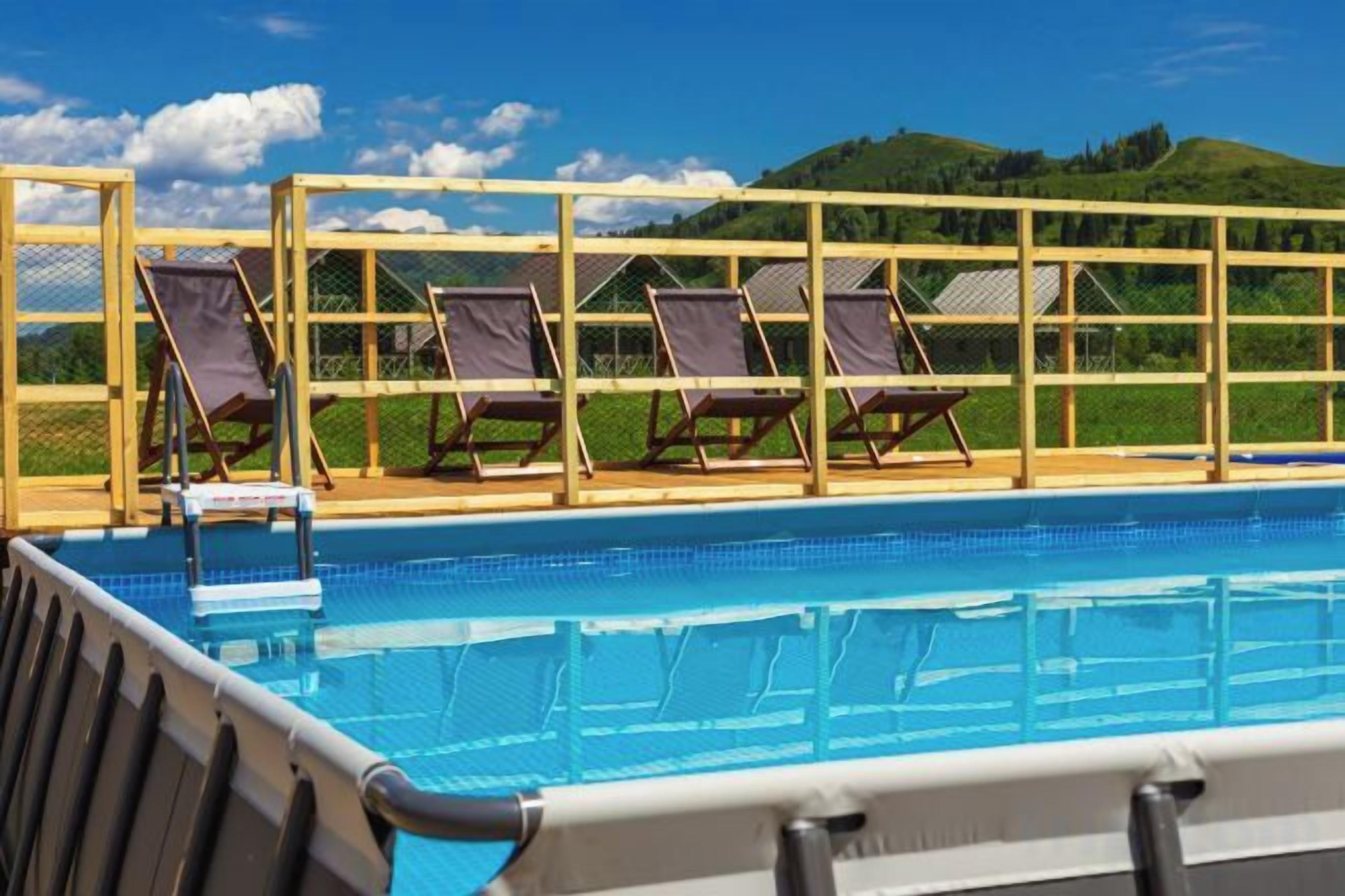A swimming pool with sun loungers and a view of hills.