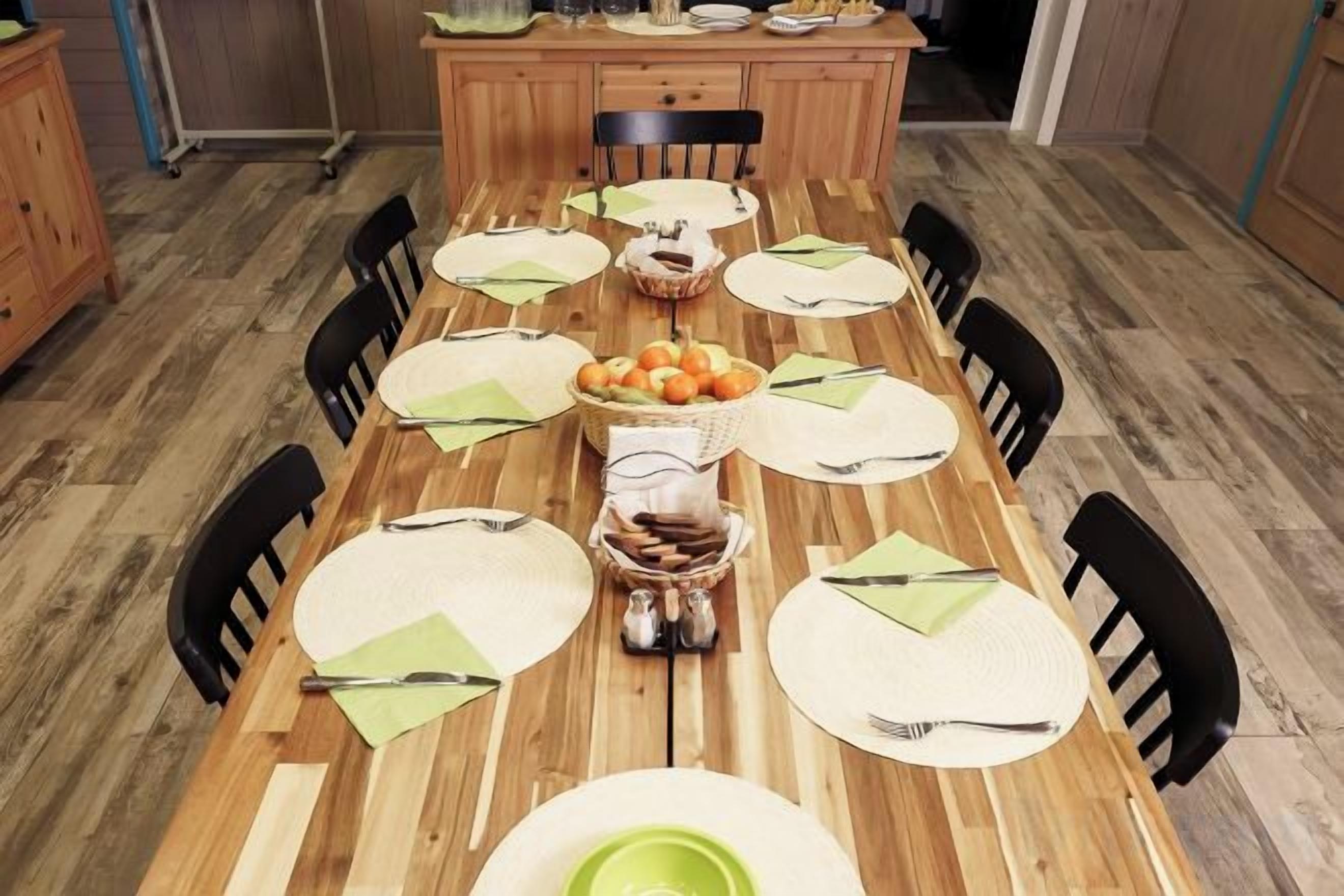 A dining table set with placemats, plates, and a centerpiece of oranges and bread.