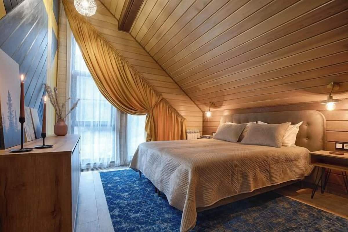 Een slaapkamer met een groot bed, een houten plafond en een blauw tapijt met een patroon.