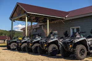 A row of ATVs parked outside a building with a covered area.