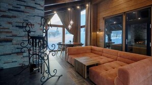 Un intérieur chaleureux avec un mur en pierre, un plafond en bois, une grande fenêtre et un coin salon.