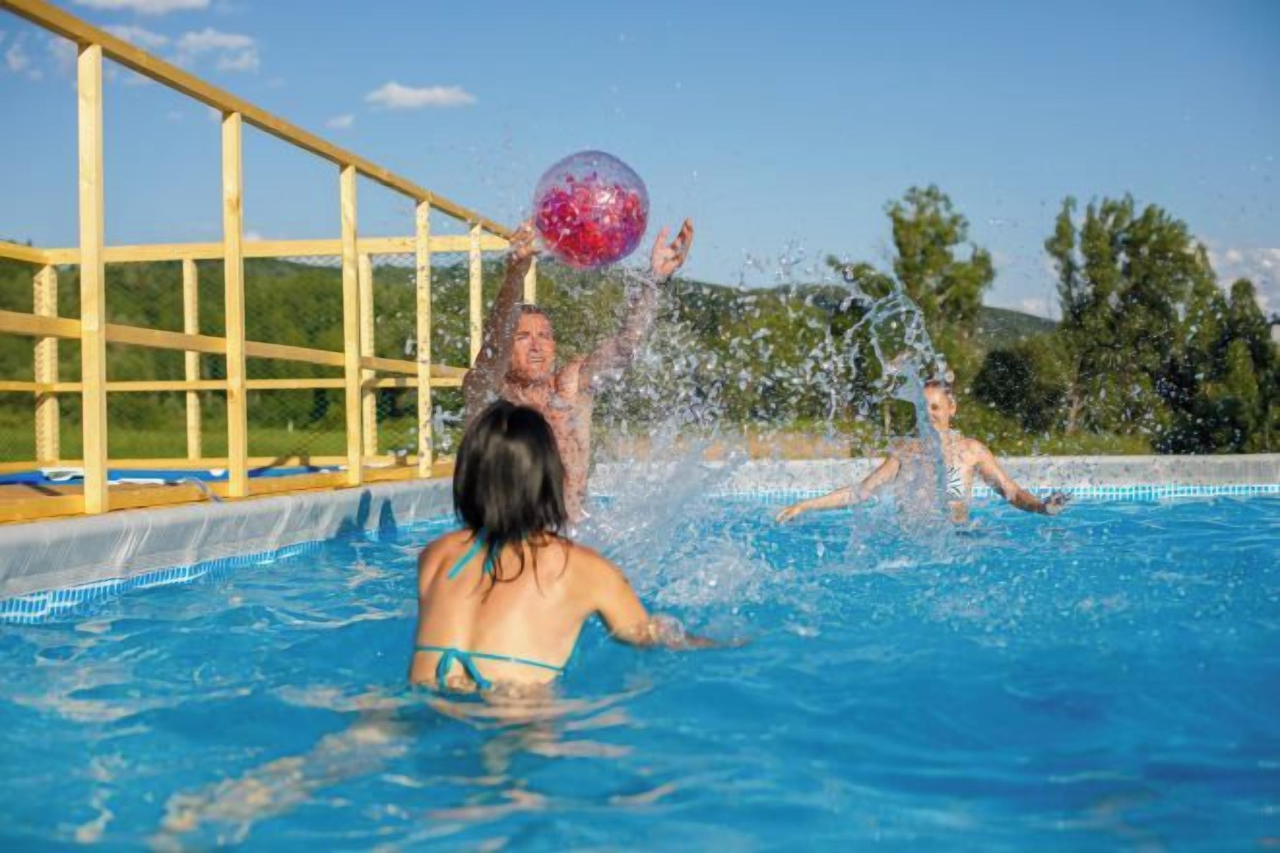 A swimming pool with people playing with a ball.