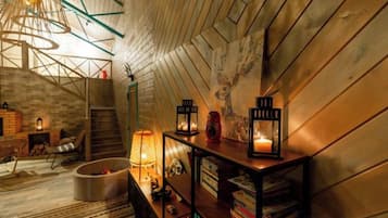 Ein Dachzimmer mit geneigter Decke, Holzwänden, einer Wendeltreppe und einem Bücherregal mit Büchern und Dekoration.