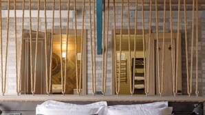Une chambre d’hôtel avec un lit, une table de chevet et un miroir agrémenté de rideaux en corde.