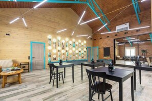 A spacious room with wooden walls, a high ceiling, and a seating area with tables and chairs. - Park-Hotel "Zarechye" (Glubokoye District)