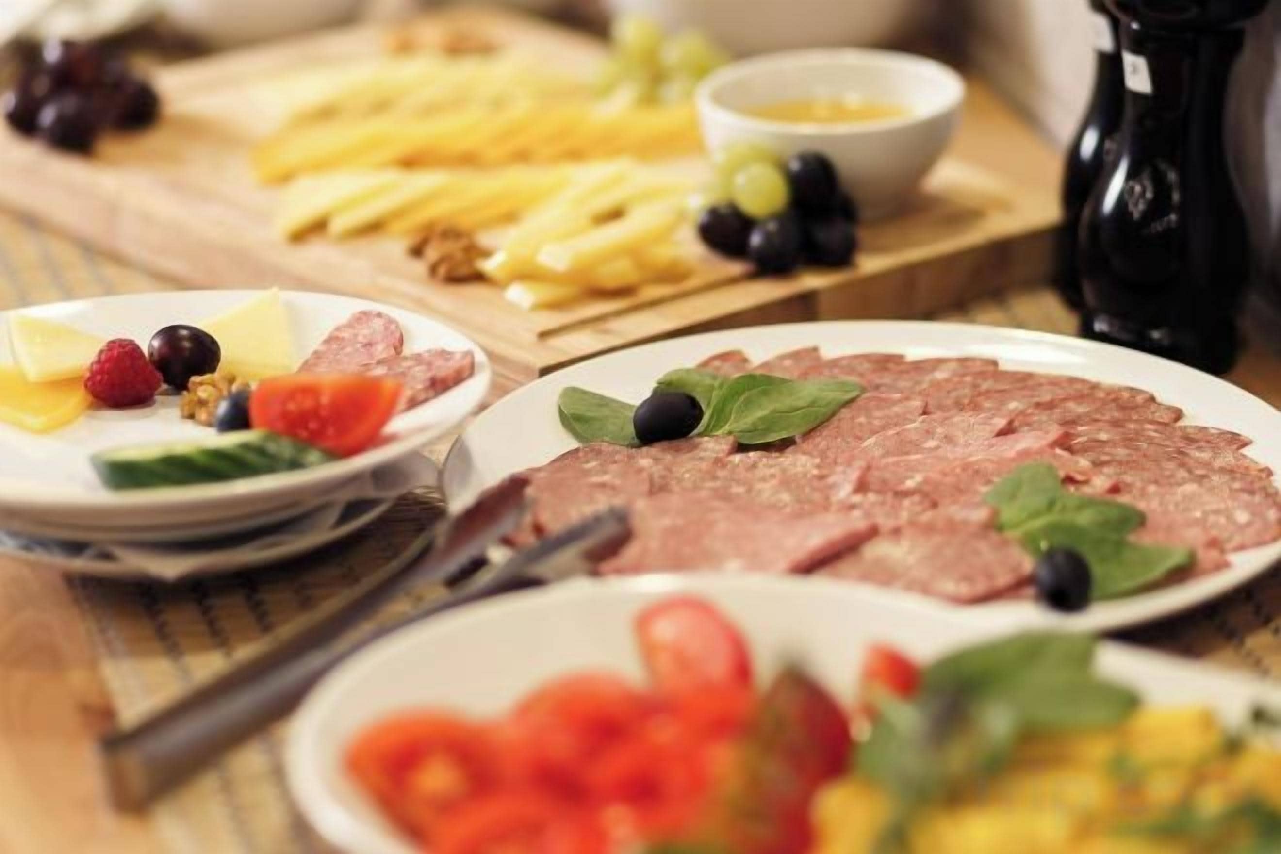 A table with various food items including cheese, meat, and fruits.