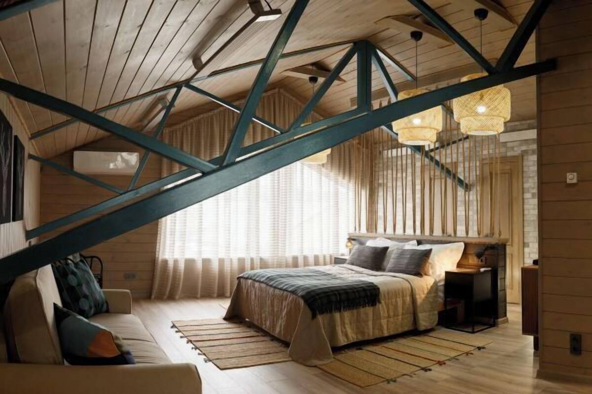 Een slaapkamer met een schuine kap, een bed, een slaapbank en een nachtkastje.