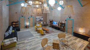 Un loft spacieux avec un plafond haut, des poutres apparentes et différents espaces de détente, notamment un canapé, des fauteuils et une petite table.
