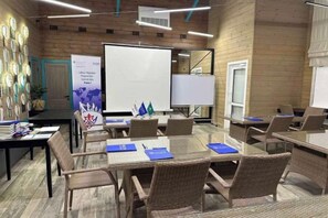Ein Konferenzraum mit großem Tisch, Stühlen, einer Whiteboard-Wand und einer Präsentationsleinwand.