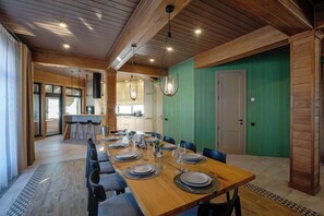 Een eetgedeelte met een lange houten tafel, gedekt voor een maaltijd, omringd door stoelen.