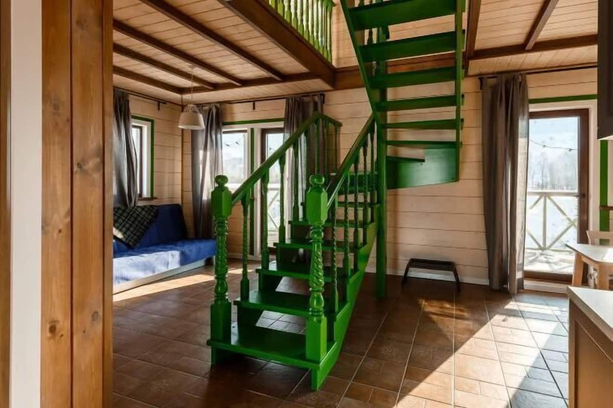 Een kamer met een houten trap, een bank en een raam.