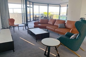 A modern living room with a sofa, armchair, coffee table, and a dining area with chairs and a table. - The 183 (Mount Pleasant)