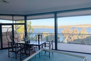 Een ruim balkon met een pooltafel, een eethoek en uitzicht op een waterpartij.