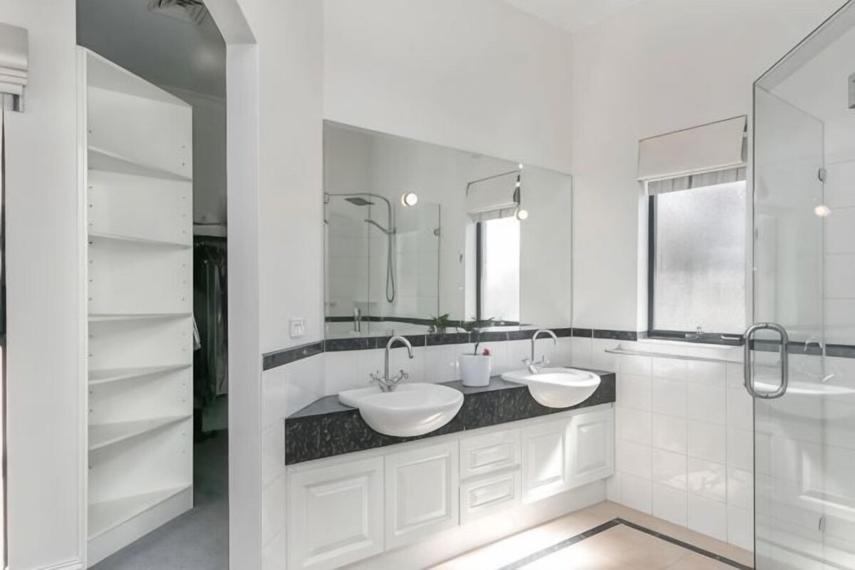 A modern bathroom with a glass shower enclosure, a double sink vanity, and a large mirror.