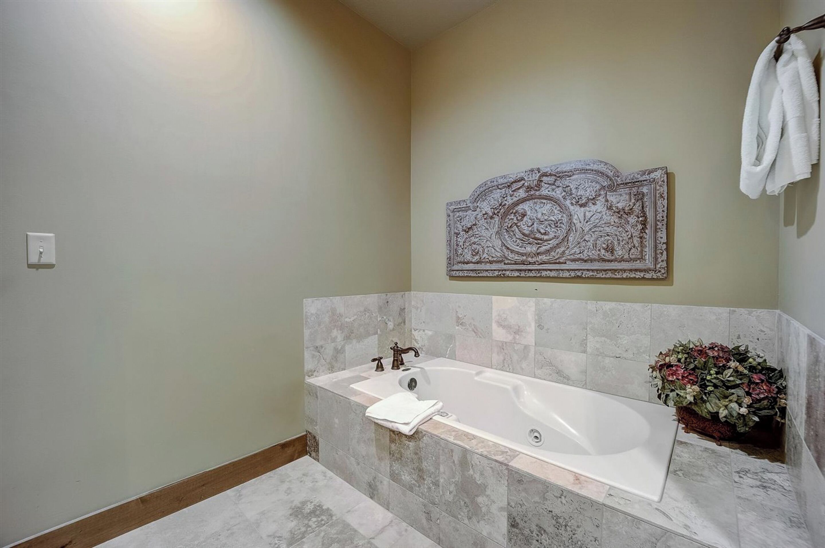 Un baño con una bañera independiente, un cabecero decorativo y una planta en maceta.