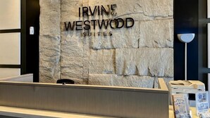 A reception desk with a stone wall background and the text 'IRVINE WESTWOOD SUITES'. - Newly 1BR Apt Cikarang with Pool Gym & Wi-Fi (Bekasi Regency)