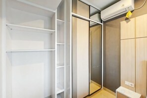 A walk-in closet with open shelving, a sliding door closet, and a built-in heater. - Newly 1BR Apt Cikarang with Pool Gym & Wi-Fi (Bekasi Regency)
