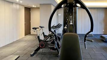 A home gym with exercise equipment, a bench, and a door leading to another room.