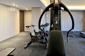 Un gimnasio en casa con equipo de ejercicio, una banca y una puerta que da a otra habitación.