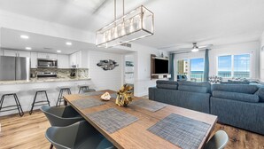A modern kitchen with a central island, bar stools, and a dining table with placemats.