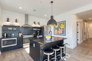 Una cucina moderna con isola centrale, elettrodomestici in acciaio inossidabile e sgabelli da bar.