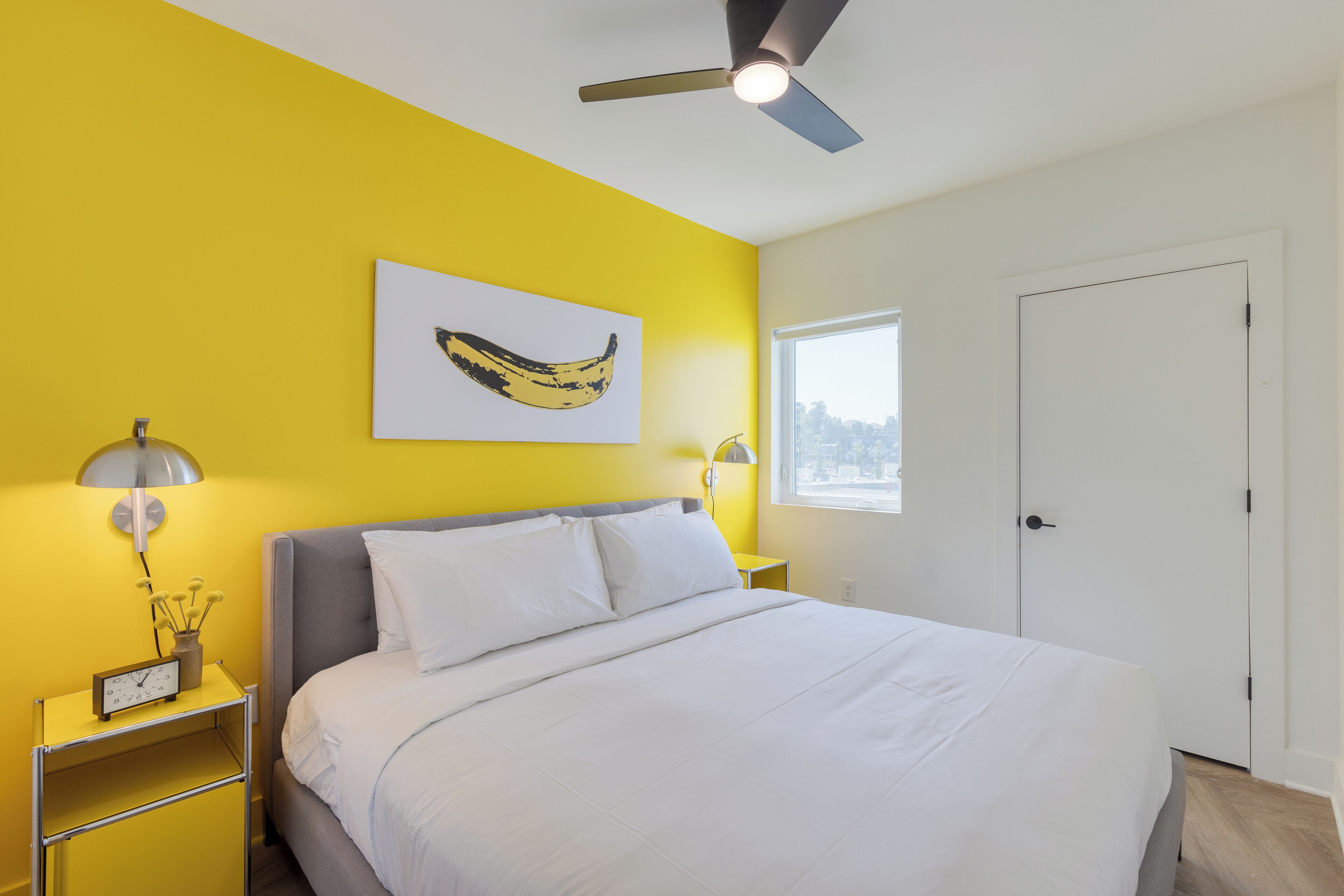 Ein Schlafzimmer mit Bett, Deckenventilator, Fenster und Tür.