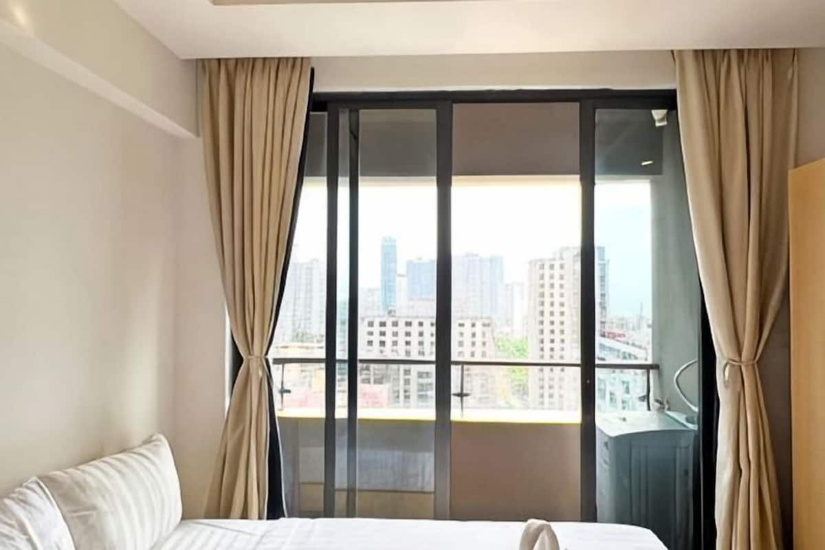 Une chambre d’hôtel avec une grande fenêtre, un lit et des rideaux.