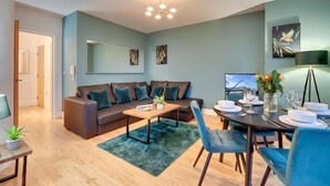 A modern living room with a sofa, coffee table, dining table set for four, and a TV. - Friarsgate Apartment by Week2Week (Newcastle)