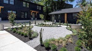 A modern two-story building with a black exterior and a landscaped garden area. - Sleeps 48, Entire Hotel, Group Retreat | The Nomad (Nashville)