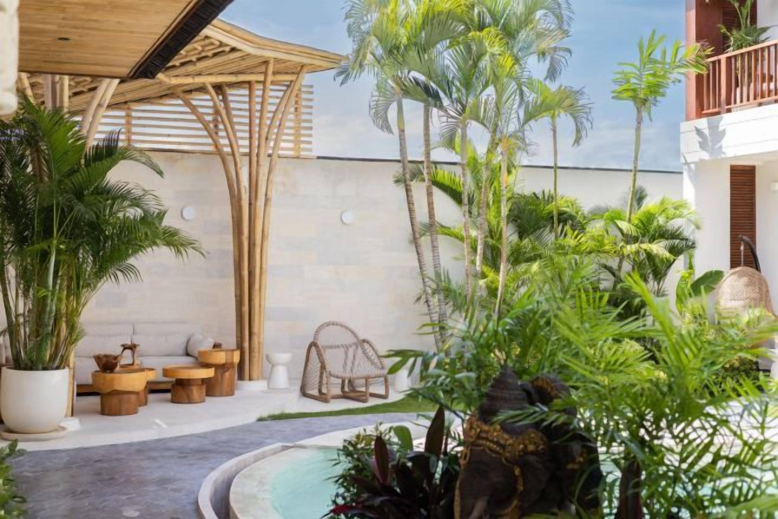 Un espace extérieur de style tropical, doté d’une pergola en bois, de sièges et d’une végétation luxuriante.